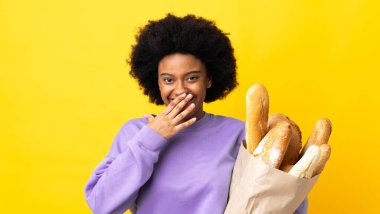 Genç Afrikalı Amerikalı bir kadın sarı arka planda izole edilmiş bir şey alıyor mutlu ve gülümseyen bir ağızla el ele tutuşuyor.