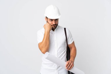 Miğferli ve elinde planları olan genç mimar yorgun ve sıkılmış bir ifadeyle beyaz arka planda izole edilmiş.