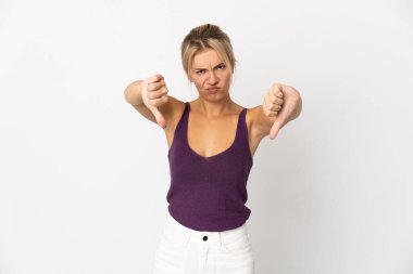 Beyaz arka planda izole edilmiş genç bir Rus kadın baş parmağını iki eliyle aşağı gösteriyor.