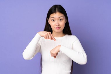 Mor arka planda izole edilmiş genç Asyalı kadın geç kalma jesti yapıyor.