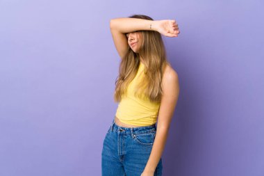 İzole edilmiş mor arka planı olan genç bir kadın gözlerini elleriyle kapatıyor.