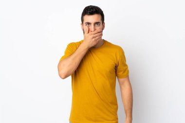 Beyaz arka planda sakallı, ağzı elle kaplanmış yakışıklı bir genç.