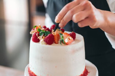 Genç pasta şefi mutfakta geleneksel kırmızı kadife kek pişiriyor.