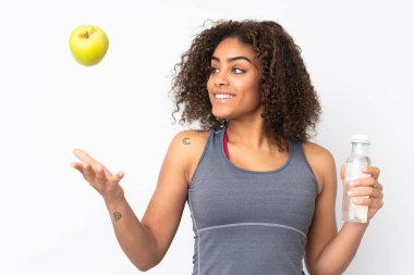 Beyaz arka planda, bir elma ve bir şişe suyla izole edilmiş genç bir Afrikalı Amerikalı kadın.