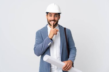 Miğferli ve elinde planları olan genç bir mimar beyaz arka planda bir sessizlik işareti gösteriyor. Parmağını ağzına sok.
