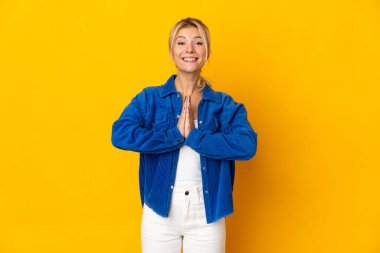 Sarı arka planda izole edilmiş genç Rus kadın avuç içlerini bir arada tutuyor. İnsan bir şey ister.