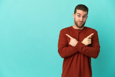 Soyutlanmış mavi arka planda yakışıklı sarışın bir adam. Yan taraftakilerin şüphelerini gösteriyor.