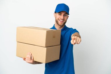İzole edilmiş beyaz arka planda teslimatçı şaşırmış ve ön tarafı işaret ediyor.