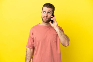 Yakışıklı sarışın adam izole edilmiş arka planda cep telefonu kullanıyor.