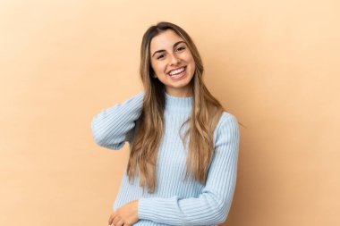 Bej arka planda izole edilmiş genç beyaz kadın gülüyor.