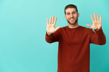 İzole edilmiş mavi arka planı olan yakışıklı sarışın adam parmaklarıyla 10 'a kadar sayıyor.