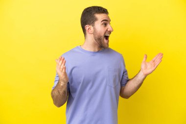 Sarışın yakışıklı, yalıtılmış sarı arka planda, şaşırmış bir yüz ifadesi var.