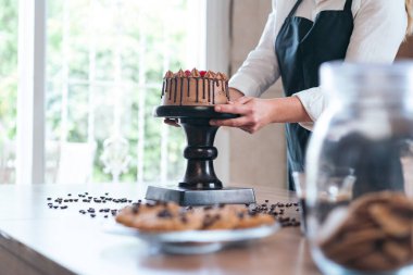 Genç pasta şefi mutfakta meyveli ev yapımı çikolatalı kek pişiriyor.