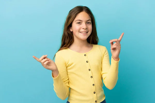 小さなCaucasian女の子隔離された上の青の背景指差す指にザ ラテラルと幸せな — ストック写真