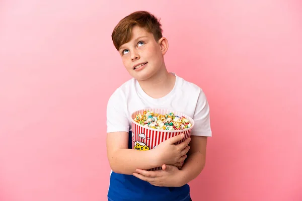Mały Rudowłosy Chłopiec Odizolowany Różowym Tle Trzymając Duży Wiadro Popcornów — Zdjęcie stockowe
