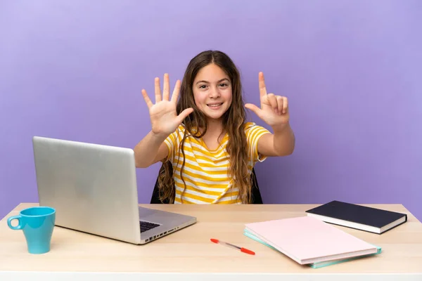 Little student girl in a workplace with a laptop isolated on purple background counting seven with fingers