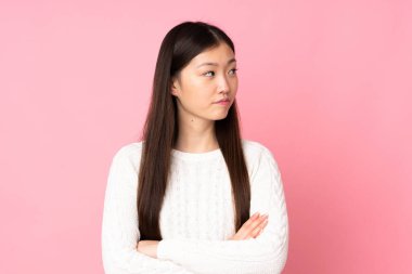 Asyalı genç bir kadın kollarını çapraz tutuyor.