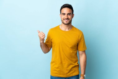 Tecrit edilmiş genç yakışıklı bir adam bir ürün sunmak için kenarı işaret ediyor.