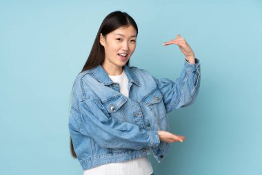 Arka planda izole edilmiş genç Asyalı bir kadın ilan vermek için kopyalama alanı tutuyor.