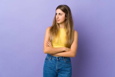 İzole edilmiş mor arka planda genç bir kadın kollarını çapraz tutuyor.