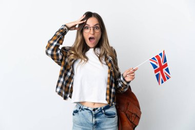Beyaz zemin üzerinde sürpriz bir ifadeyle izole edilmiş bir Birleşik Krallık bayrağı tutan genç Romen kadını