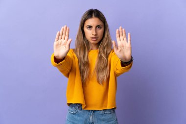 İzole edilmiş mor arka planda genç İspanyol kadın dur hareketi yapıyor ve hayal kırıklığına uğruyor.