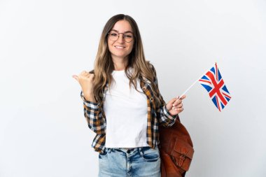 Beyaz arka planda izole edilmiş bir Birleşik Krallık bayrağı taşıyan genç Romen kadın, bir ürün sunmak için kenarı işaret ediyor