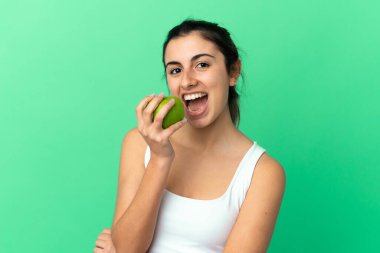 Yeşil arka planda izole edilmiş beyaz bir kadın elma yiyor.