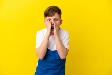 Küçük kızıl saçlı çocuk sarı arka planda izole edilmiş bağırıyor ve bir şeyler söylüyor.