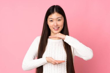 Asyalı genç bir kadın, izole edilmiş arka planda bir ilan vermek için avucunun içinde hayali bir mekan tutuyor.