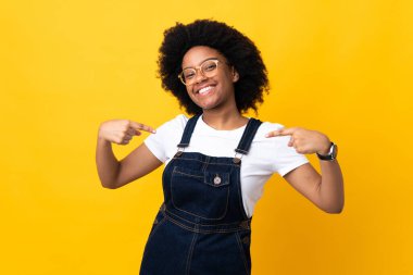 Sarı arka planda kendini beğenmiş ve gururlu genç Afrikalı Amerikalı kadın.