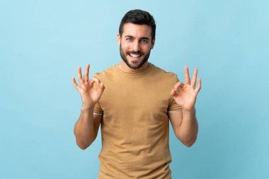 Sakallı, sakallı, genç ve yakışıklı bir adam. İki eliyle tamam işareti gösteriyor.