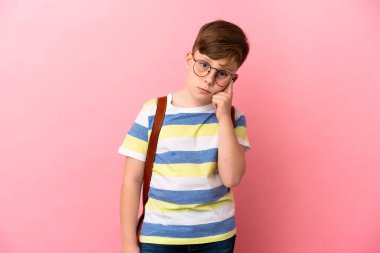 Küçük kızıl saçlı beyaz çocuk pembe arka planda izole edilmiş bir fikir düşünüyor.