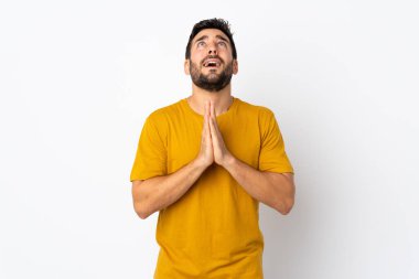 Beyaz arka planda sakallı genç yakışıklı adam avuç içlerini bir arada tutuyor. İnsan bir şey ister.