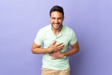 Mor arka planda izole edilmiş genç yakışıklı adam çok gülümsüyor.