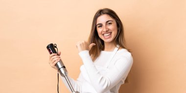 Arkaplanda el blenderi kullanan gururlu ve kendini beğenmiş bir kadın.