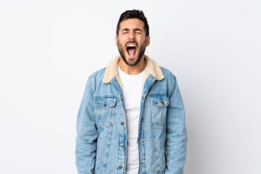 Beyaz arka planda sakallı yakışıklı genç adam ağzı açık bağırıyor.
