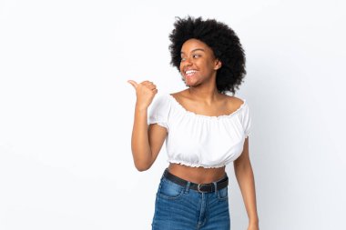 Beyaz arka planda izole edilmiş genç Afrikalı Amerikalı kadın bir ürünü sunmak için kenarı işaret ediyor.