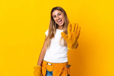 Genç İspanyol elektrikçi kadın izole edilmiş sarı duvarın üzerinde parmaklarıyla beşi sayıyor.