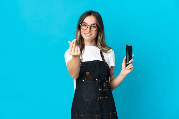Young Romanian hairdresser woman isolated on blue background making money gesture