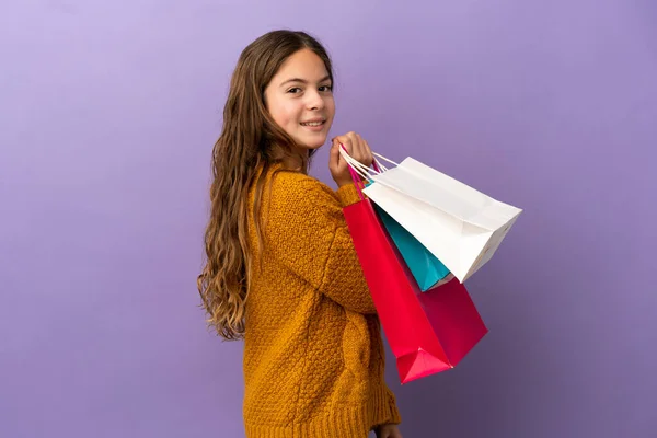 Klein Blank Meisje Geïsoleerd Paarse Achtergrond Holding Boodschappentassen Glimlachen — Stockfoto