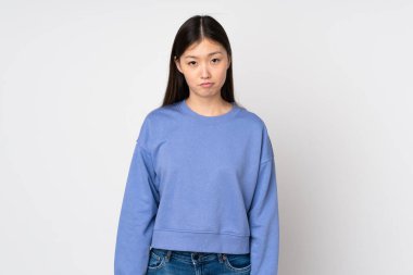 Asyalı genç bir kadın üzgün bir ifadeyle arka planda izole edilmiş.