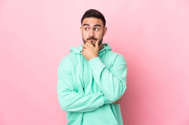 Pembe arka planda soyutlanmış beyaz, yakışıklı genç bir adam. Şüpheleri ve düşünceleri var.