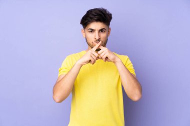 Münzevi geçmişi olan yakışıklı Arap bir adam sessizlik işareti gösteriyor.