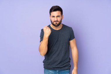 İzole edilmiş mor arka planda mutsuz suratlı beyaz yakışıklı bir adam.