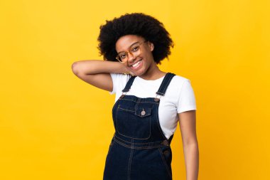 Genç Afrikalı Amerikalı kadın sarı arka planda yalnız gülüyor.
