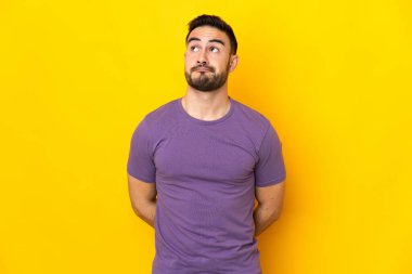 Beyaz tenli yakışıklı adam sarı arka planda izole edilmiş ve yukarı bakıyor.