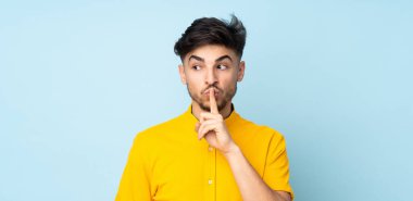Münzevi bir geçmişi olan Arap yakışıklı bir adam sessizlik işareti gösteriyor. Parmağını ağzına sokuyor.