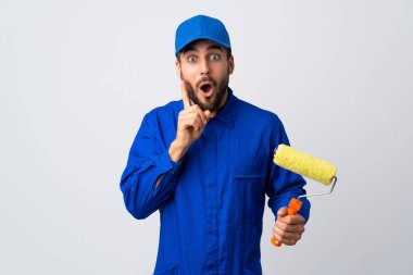 Ressam beyaz arka planda izole edilmiş bir boya silindiri tutuyor. Çözümü bulmak için parmağını kaldırıyor.