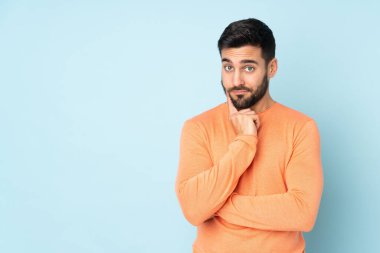 Kafkasyalı yakışıklı bir adam ve soyutlanmış mavi arka plan üzerinde düşünüyor.